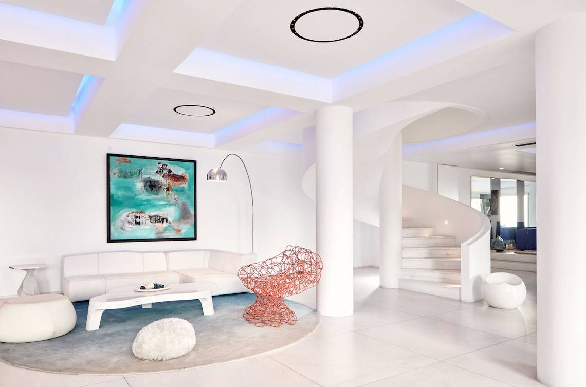 Wohnzimmer im Myconian Ambassador Relais & Chateaux Hotel mit weißem Sofa und moderner Kunst.