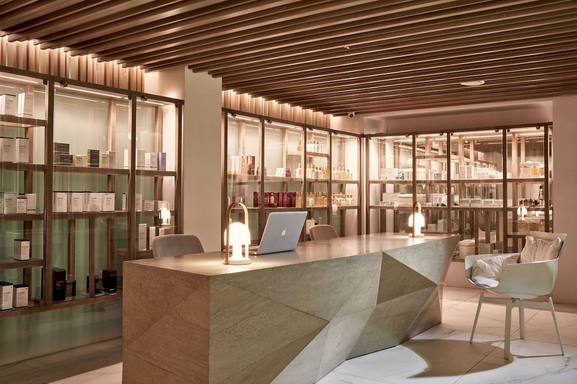 Empfangsbereich im Myconian Ambassador Relais & Chateaux mit Laptop, Lampen und Regalen.