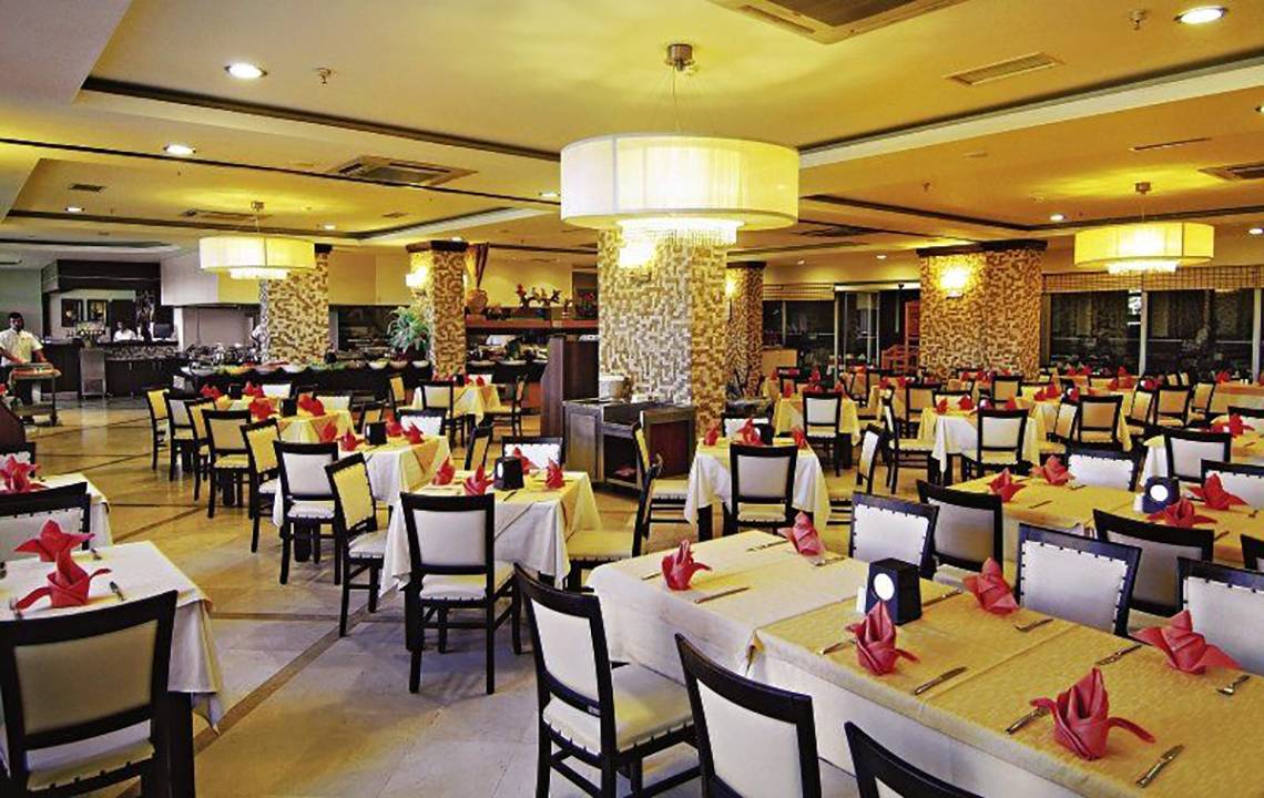 Innenansicht des Restaurants im Hotel Fun&Sun Smart Hane mit gedeckten Tischen und gelben Tischdecken.