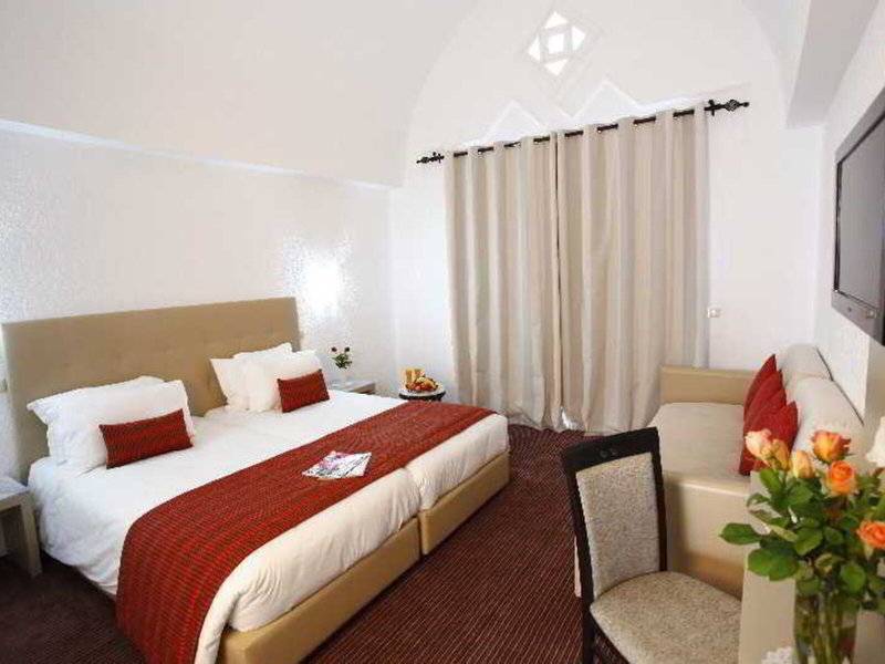 Doppelzimmer im Djerba Holiday Beach Hotel mit Doppelbett, Sofa, Tisch, Stuhl und Fernseher.