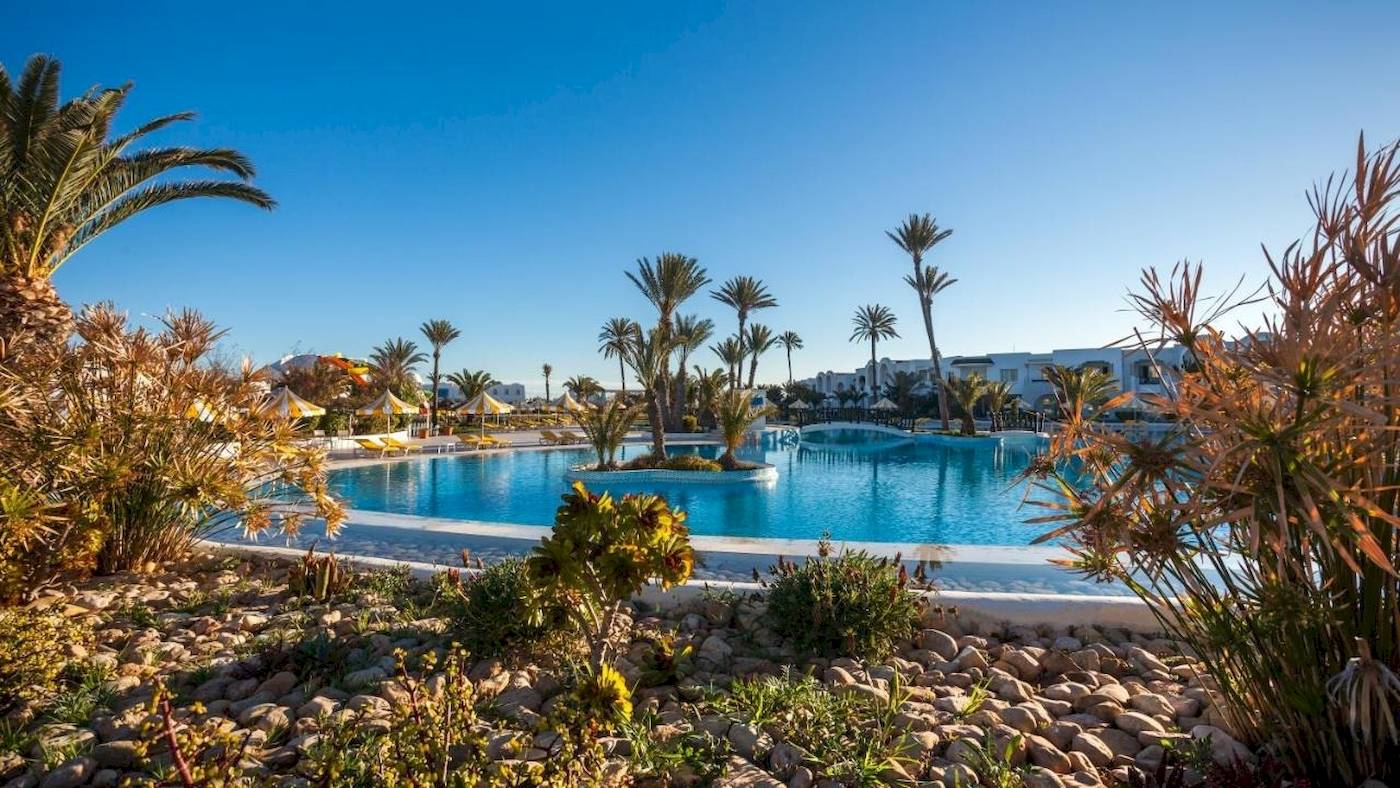 Außenbereich des Djerba Holiday Beach Hotels mit Swimmingpool, Palmen und Gebäuden