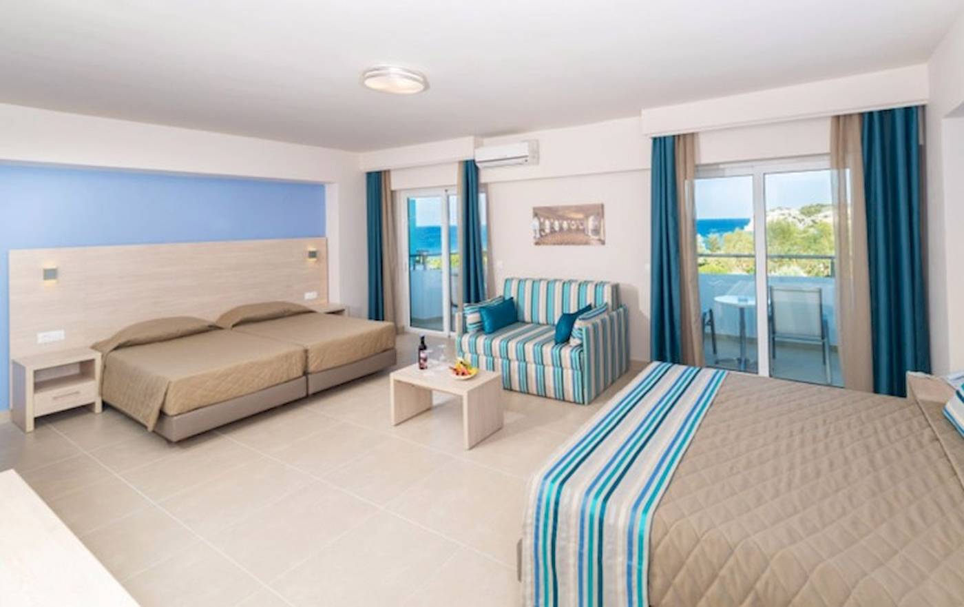 Zimmer im Irene Palace Beach Resort mit zwei Betten, einem Sofa und einem Balkon mit Meerblick.