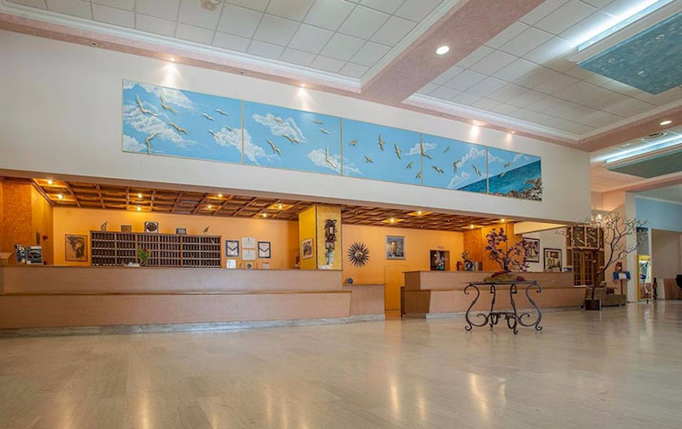 Empfangsbereich des Irene Palace Beach Resorts mit großen Wandgemälden und Möbeln.