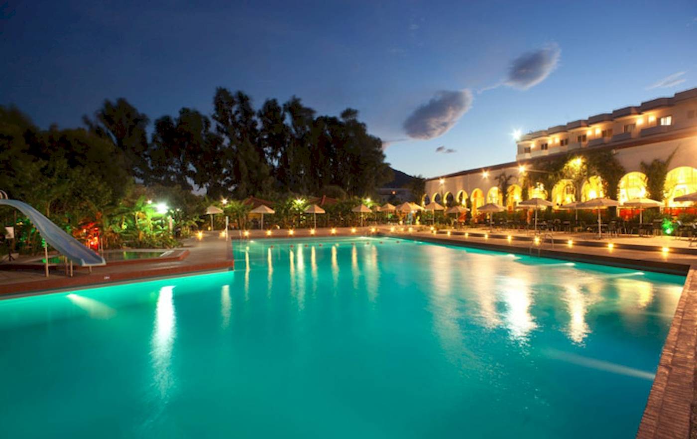 Pool des Irene Palace Beach Resorts bei Nacht mit leuchtenden Lichtern und einem Wasserrutsche