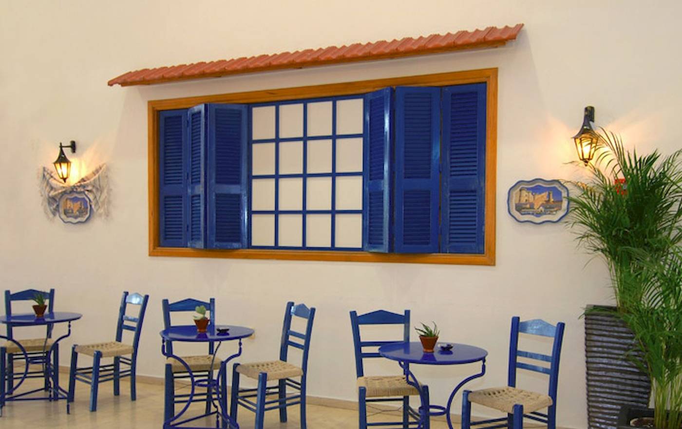 Innenbereich des Cafés im Irene Palace Beach Resort mit blauen Tischen und Stühlen.