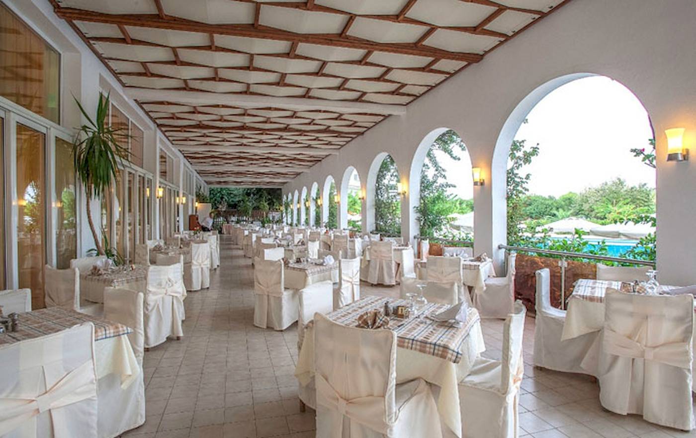 Innenbereich des Restaurants im Irene Palace Beach Resort mit gedeckten Tischen und Säulen.