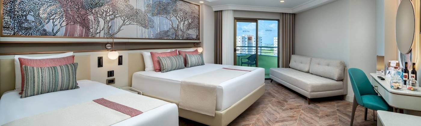 Doppelzimmer im Delphin Palace Hotel mit zwei Betten, Sofa, Schreibtisch und Terrassentür.