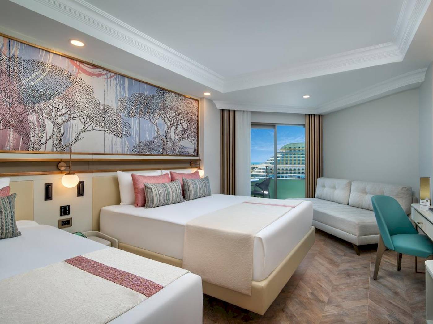 Doppelzimmer im Delphin Palast Hotel mit zwei Betten, Sofa und großer Fensterfront.