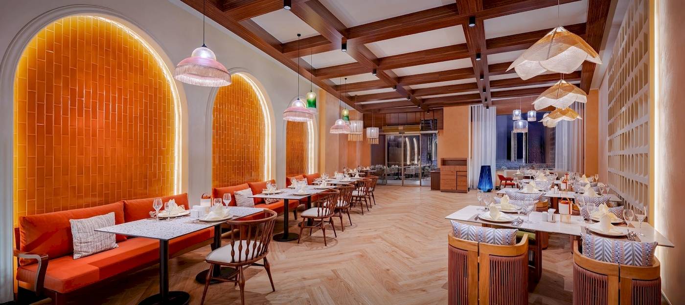 Innenbereich des Delphin Palace Restaurants mit orangefarbenen Wänden, Holztischen und Stühlen.