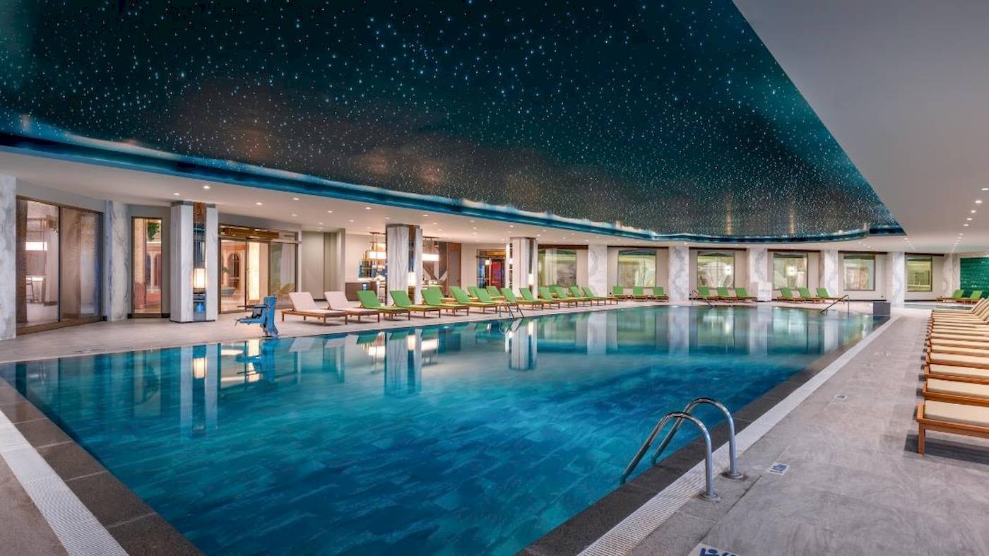 Poolbereich im Delphin Palace Hotel mit Sternenhimmeldecke und grünen Liegen