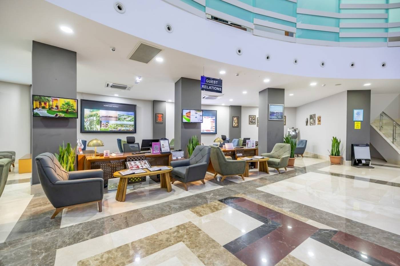 Empfangshalle des VONRESORT Golden Coast mit modernem Design, Sitzbereichen, Tischen, Pflanzen und Monitoren.