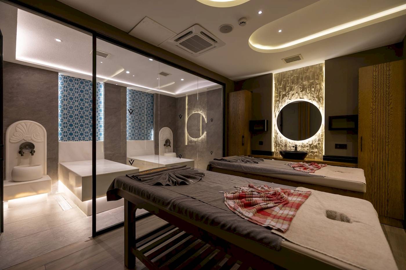 Spa-Behandlungsraum im VONRESORT Golden Coast mit zwei Massagetischen und Glaswänden.