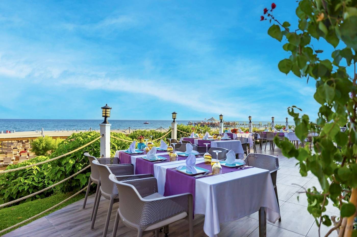 Außenterrasse des VONRESORT Golden Coast mit Tischen und Stühlen, Blick auf den Strand