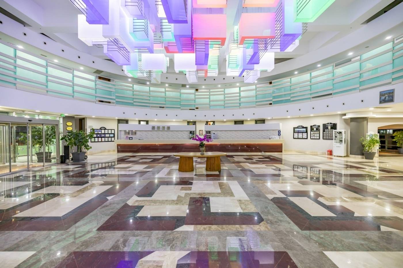Empfangsbereich des VONRESORT Golden Coast mit farbenfroher Deckenbeleuchtung und Marmorboden.