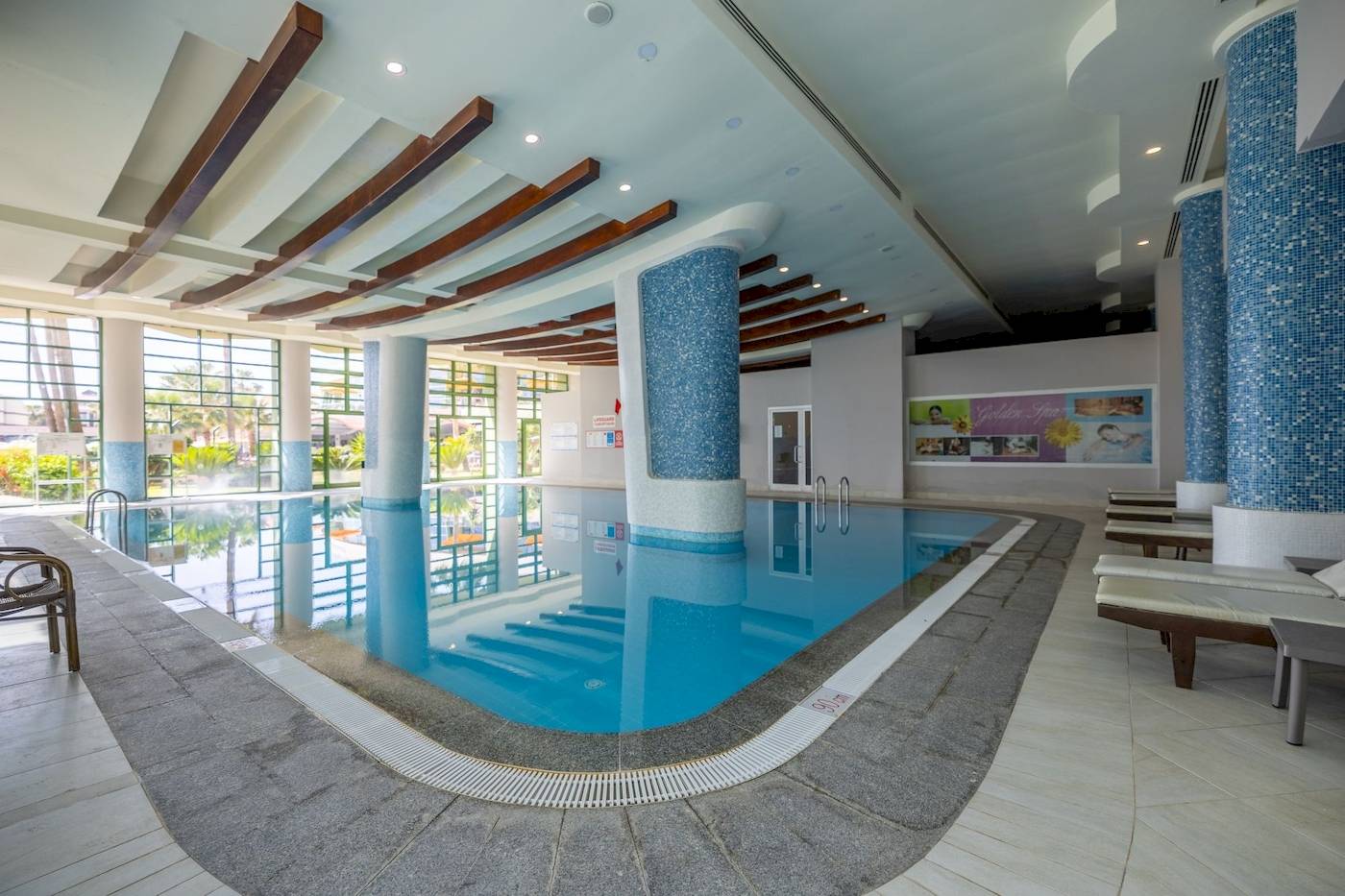 Innenpool des VONRESORT Golden Coast mit blauen Säulen und Sonnenliegen.