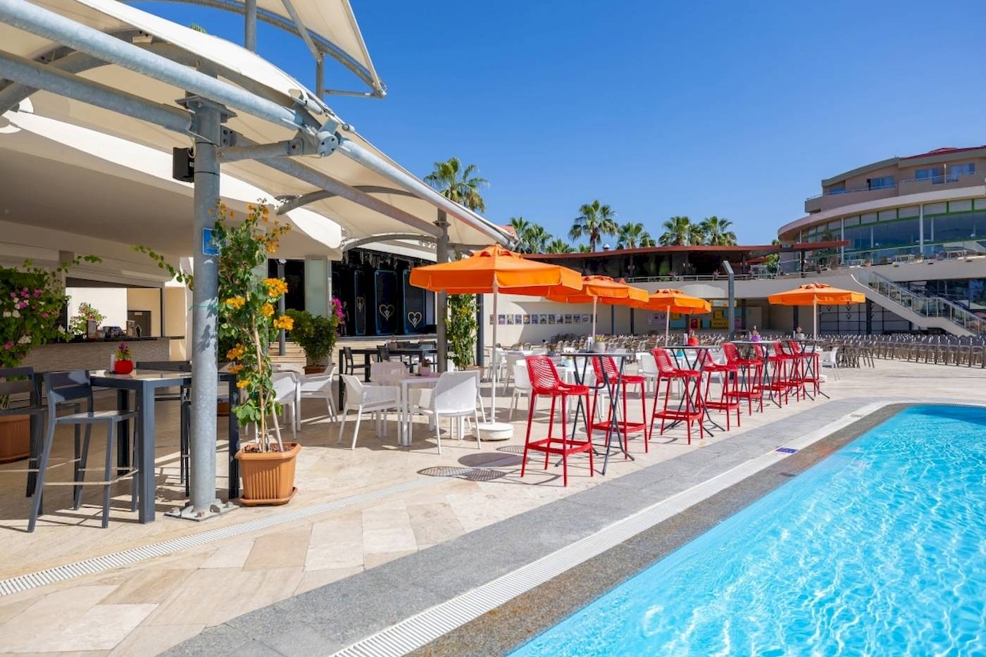 Außenbereich des VONRESORT Golden Coast mit Tischen, Stühlen und Sonnenschirmen am Pool