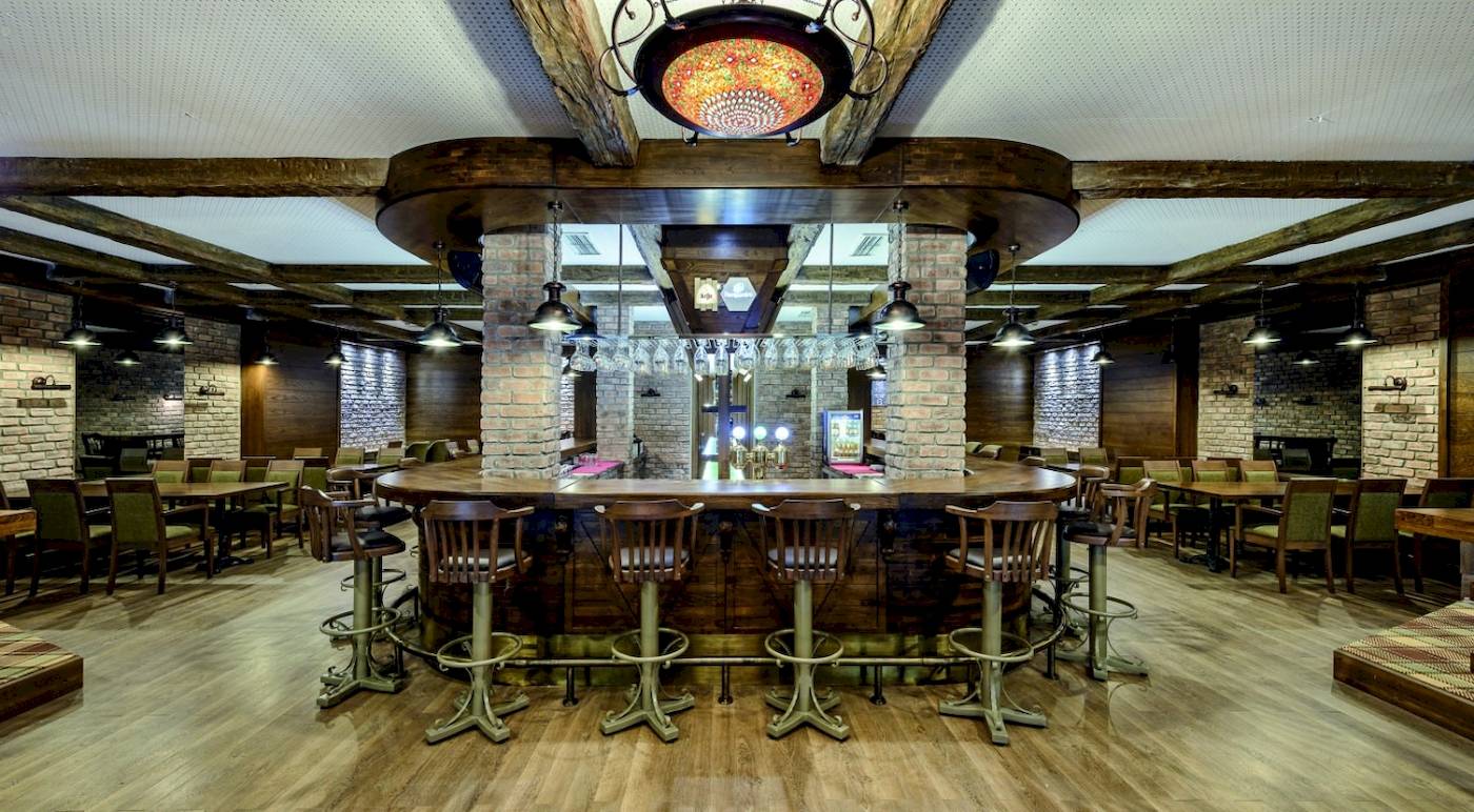 Innenansicht der Bar im VONRESORT Golden Coast mit runden Holztischen und Stühlen.