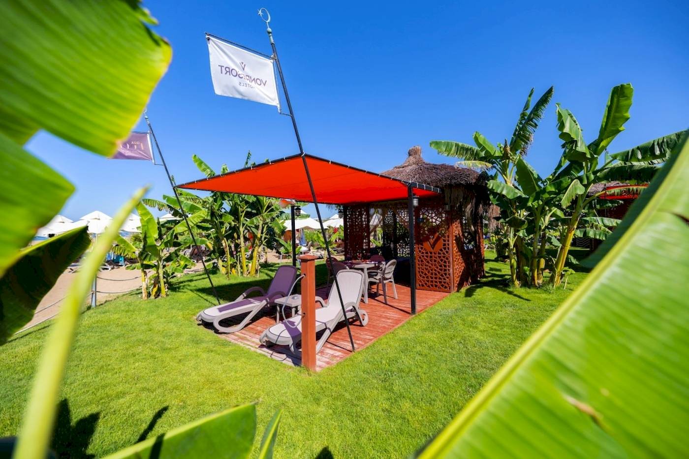 Außenbereich des VONRESORT Golden Coast mit einer Terrasse und Liegestühlen unter einem roten Baldachin.