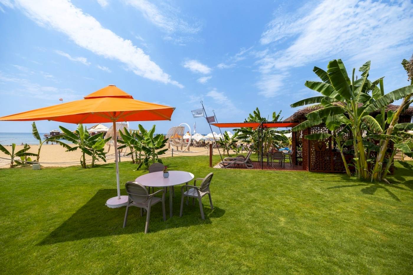 Außenbereich des VONRESORT Golden Coast mit Tisch, Stühlen und Sonnenschirm am Strand