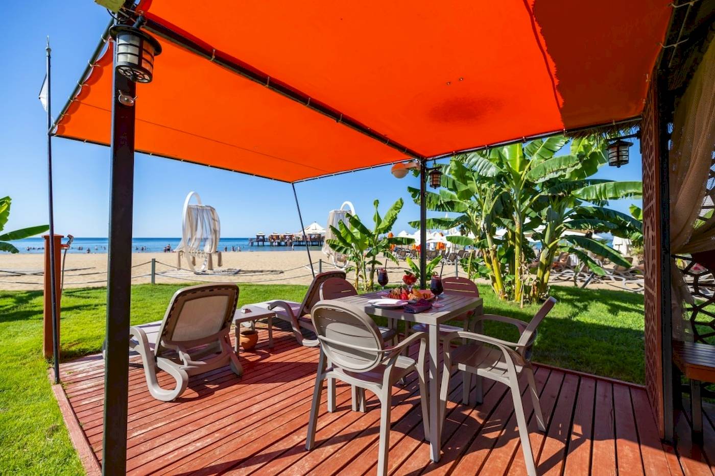 Terrasse des VONRESORT Golden Coast mit Esstisch und Sonnenschirm am Strand