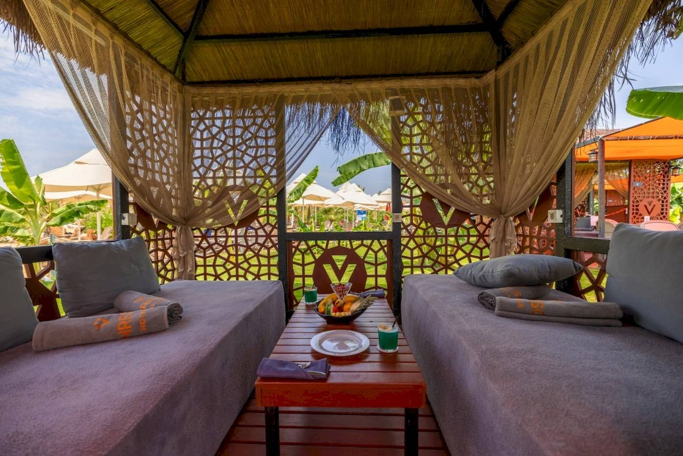 Lounge-Bereich im VONRESORT Golden Coast mit zwei Betten, Kissen und einem Tisch mit Obst.