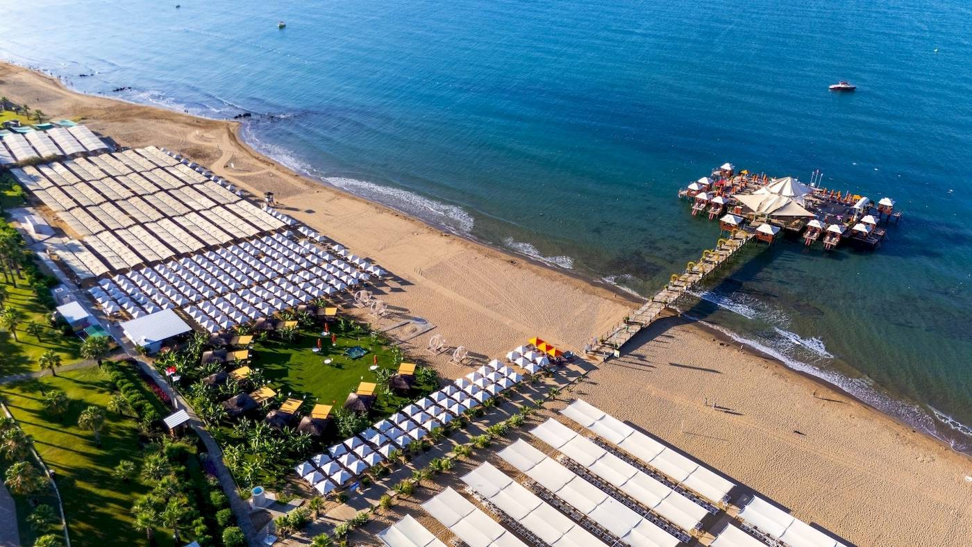 Luftaufnahme des VONRESORT Golden Coast mit vielen weißen Sonnenschirmen am Strand und einem Steg zum Meer.