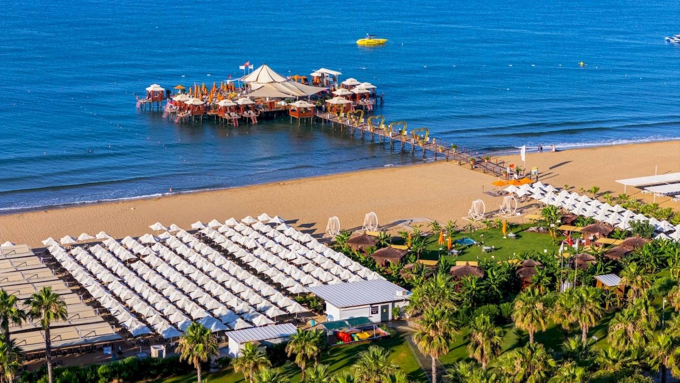 Luftaufnahme des VONRESORT Golden Coast am Strand mit vielen Sonnenschirmen und Palmen
