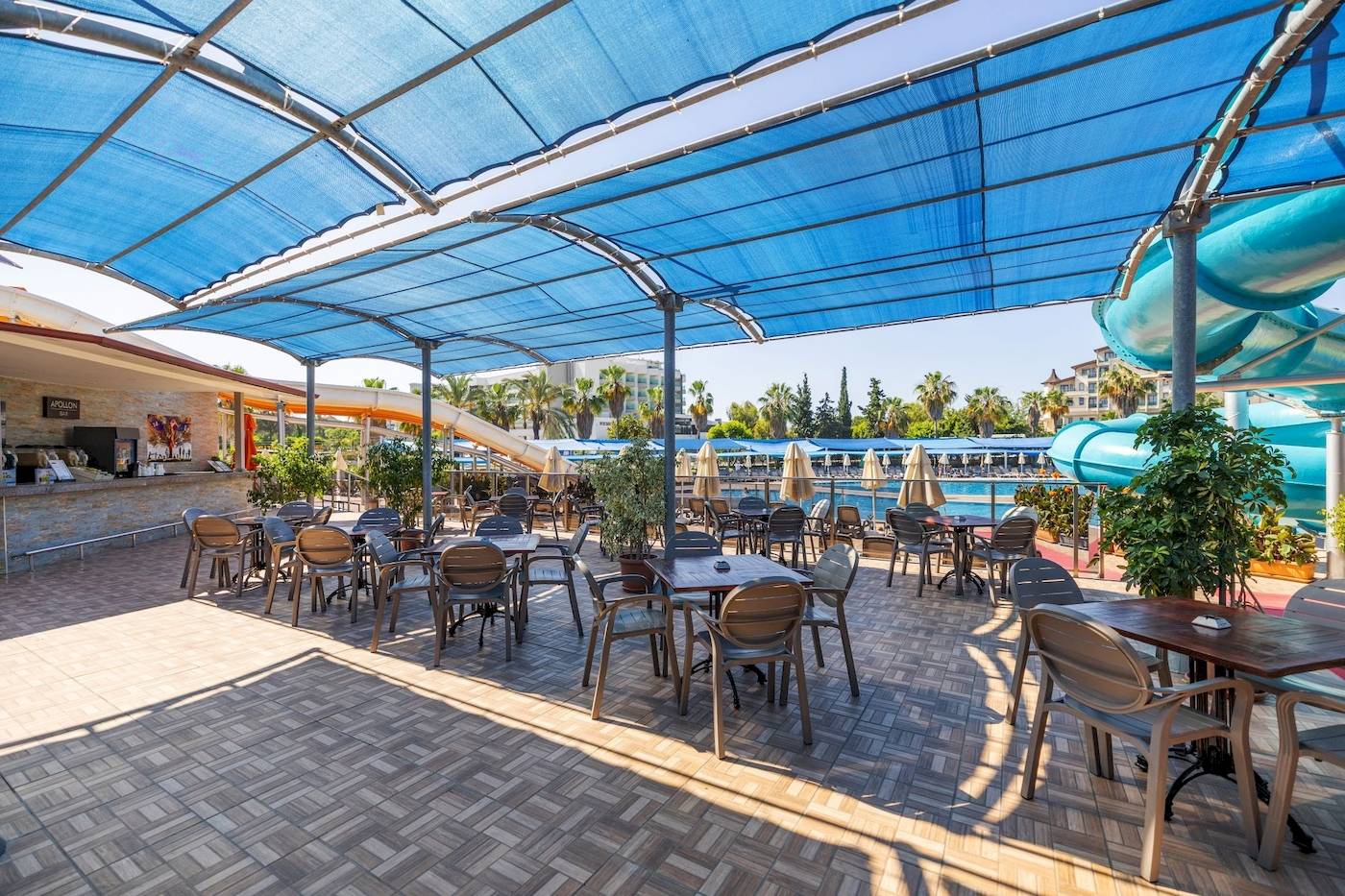 Terrasse des VONRESORT Golden Coast mit Tischen, Stühlen und blauen Markisen.