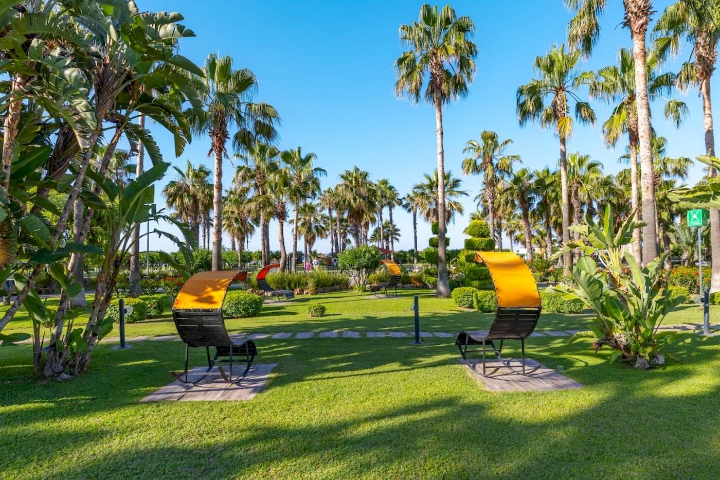 Garten des VONRESORT Golden Coast mit Liegen und Palmen im Hintergrund.