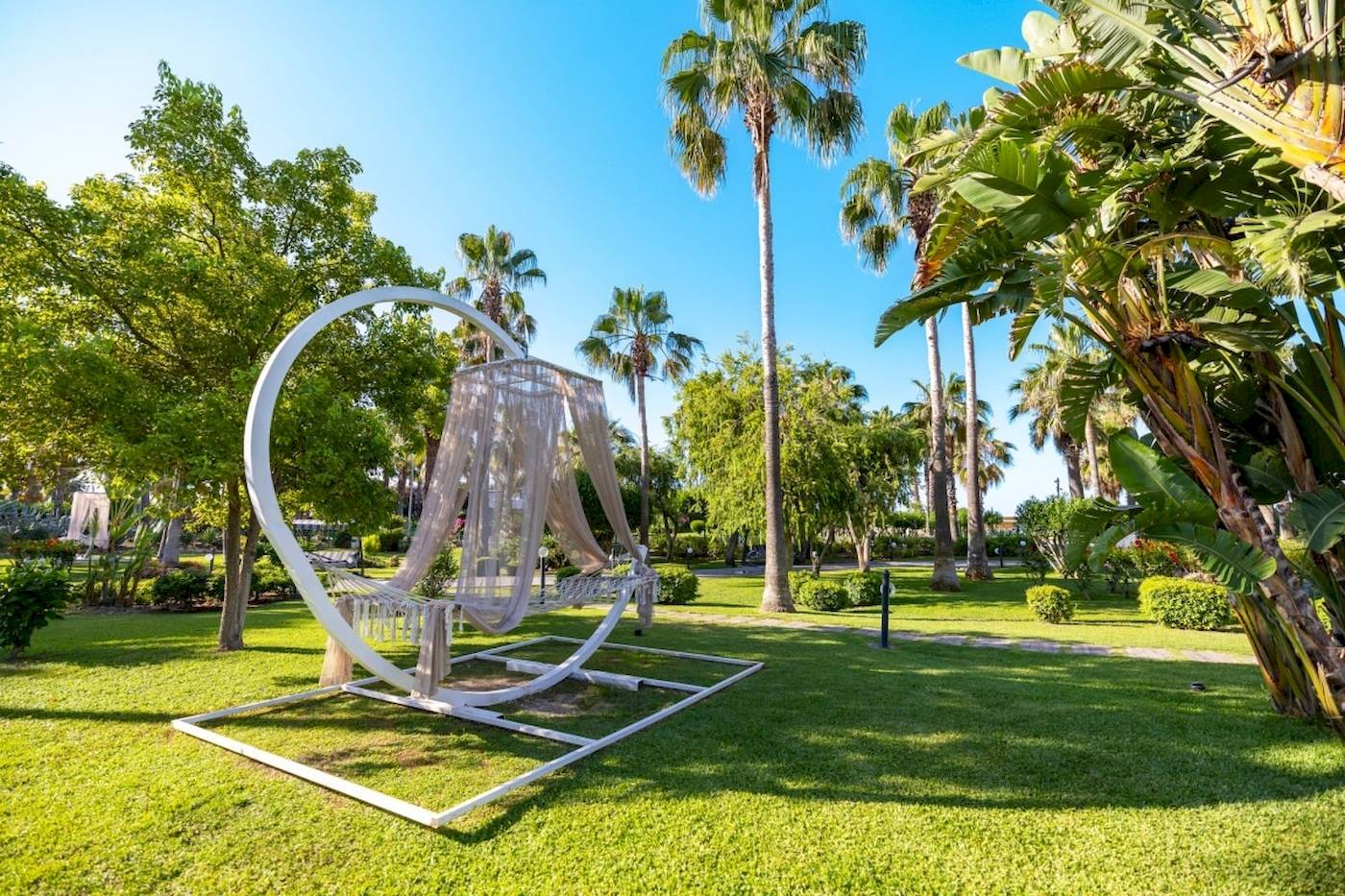 Ein Garten des VONRESORT Golden Coast mit einer weißen Hängematte und umliegenden Bäumen.