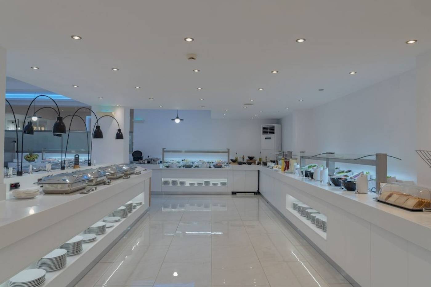 Innenansicht des Restaurants im Georgioupolis Resort Aquapark & SPA Hotel mit weißen Tischen und Buffets.