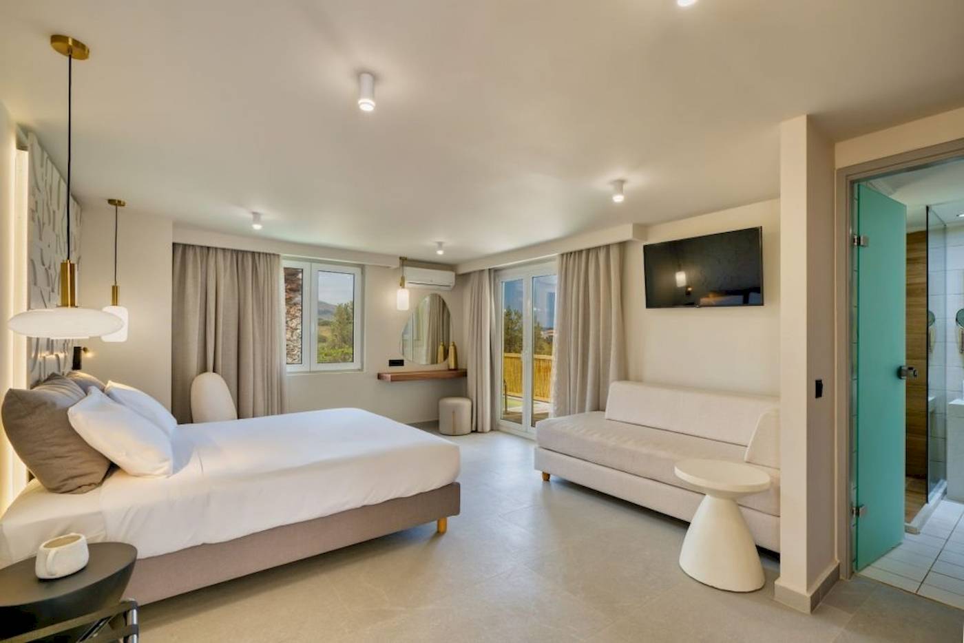 Innenansicht eines Hotelzimmers im Georgioupolis Resort Aquapark & SPA mit Bett, Sofa, Fernseher und Dusche