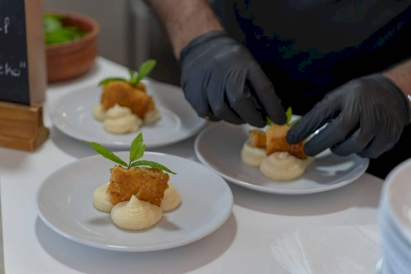 Eine Person bereitet Gerichte auf weißen Tellern im Georgioupolis Resort Aquapark & SPA vor.