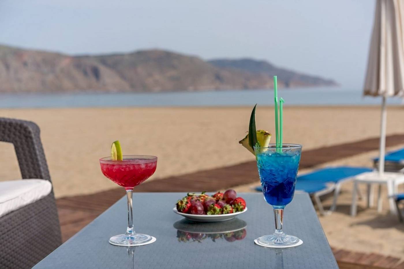 Zwei Cocktails mit Strohhalmen und Obstteller auf einem Tisch am Strand im Georgioupolis Resort.