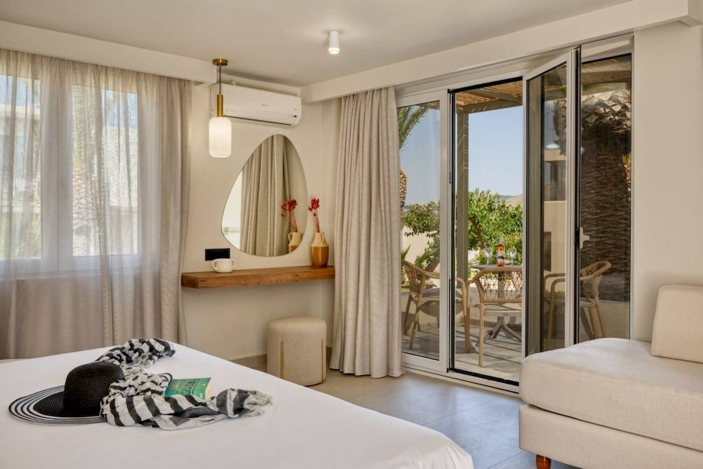 Innenansicht eines Zimmers im Georgioupolis Resort Aquapark & SPA mit großem Bett, offenem Balkon und Gartenblick.