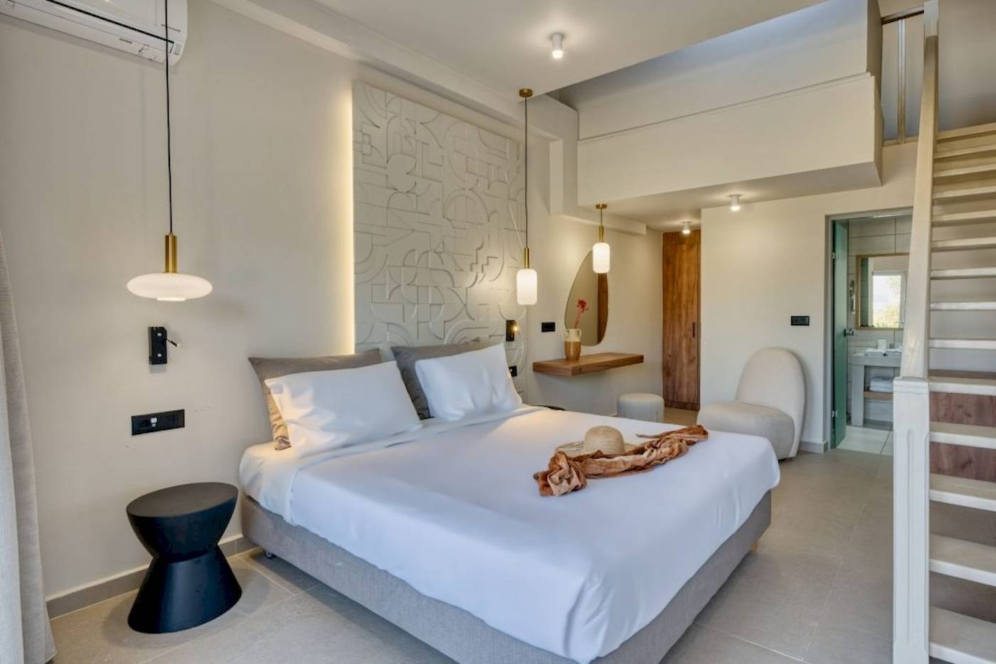 Schlafzimmer im Georgioupolis Resort Aquapark & SPA mit einem Bett, weißen Decken und einem Hut.