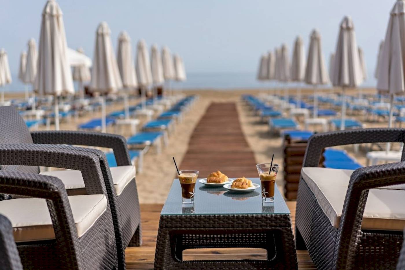 Georgioupolis Resort Aquapark & SPA Terrasse mit Tisch, Getränken und Sonneliegen.