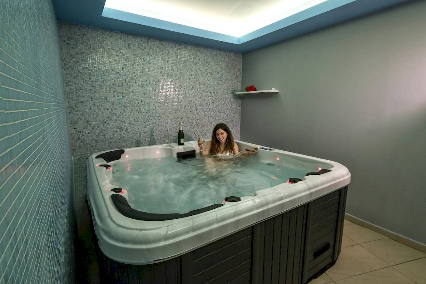 Frau im Jacuzzi im Georgioupolis Resort Aquapark & SPA mit einer Flasche und einem Glas.
