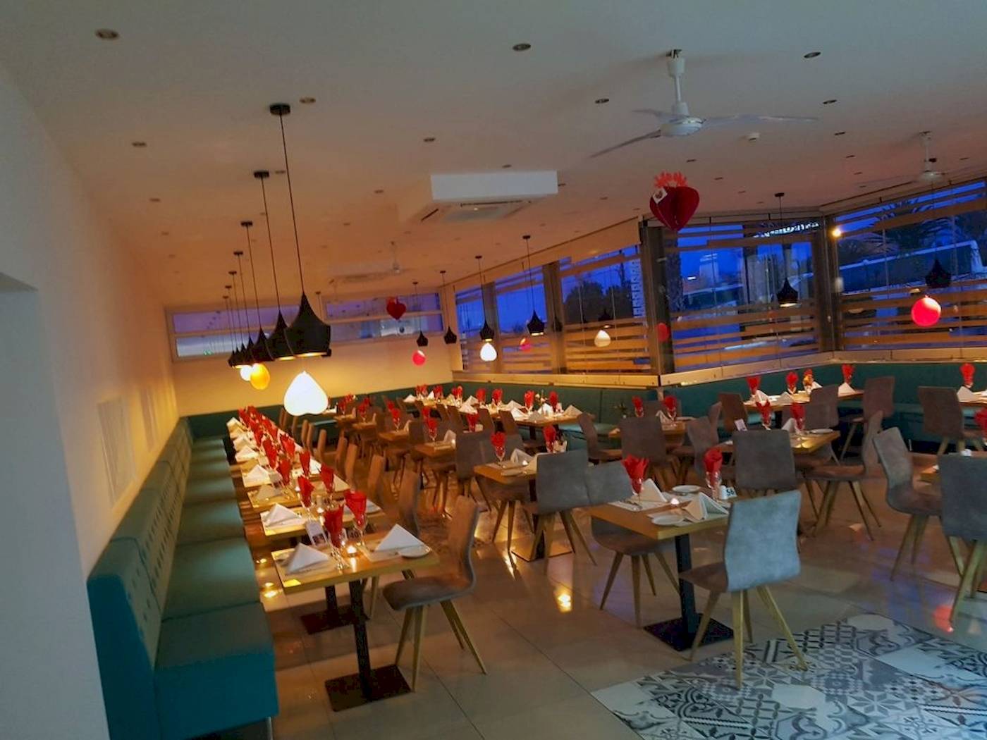 Innenbereich des Georgioupolis Resort Aquapark & SPA mit vielen gedeckten Tischen und roten Herzen an der Decke.