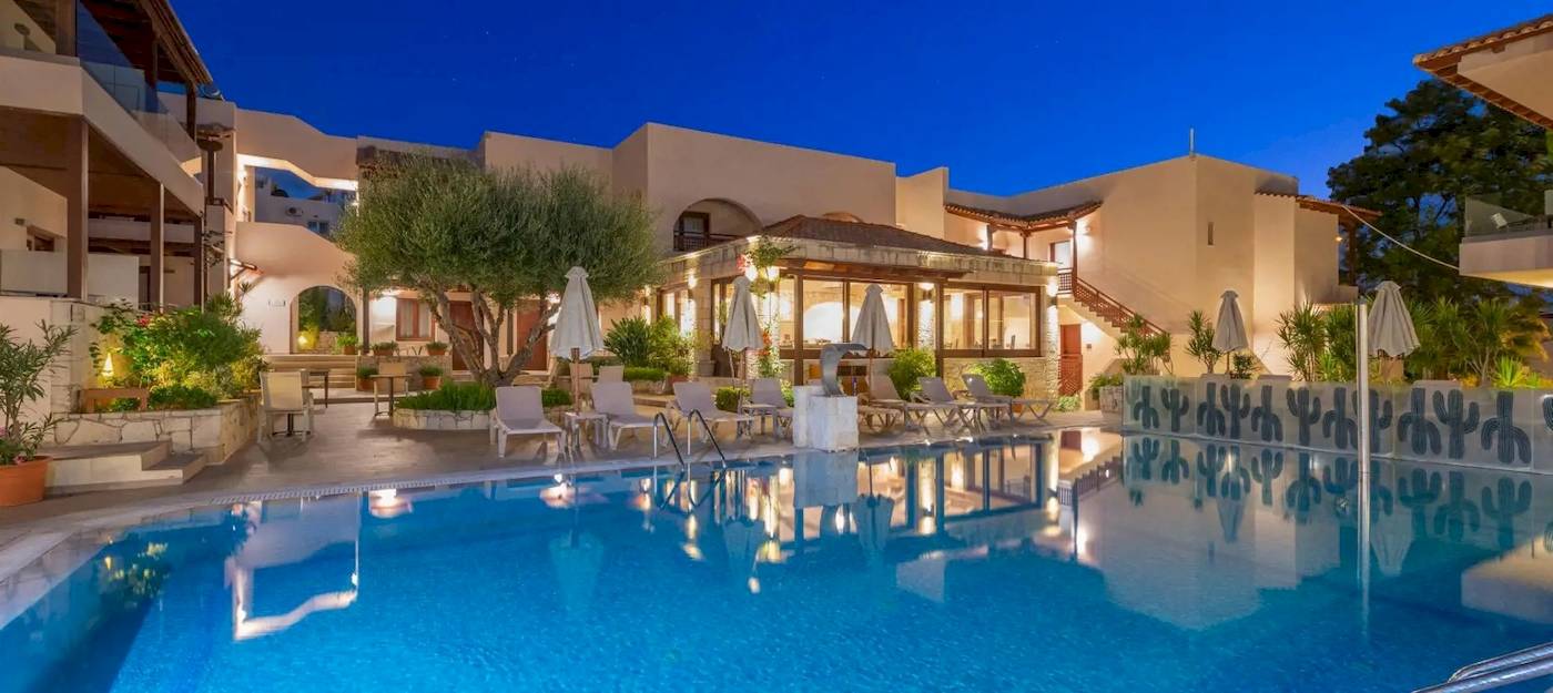 Cactus Village Hotel & Bungalows Pool bei Nachtansicht mit beleuchteten Gebäuden und Sonnenliegen