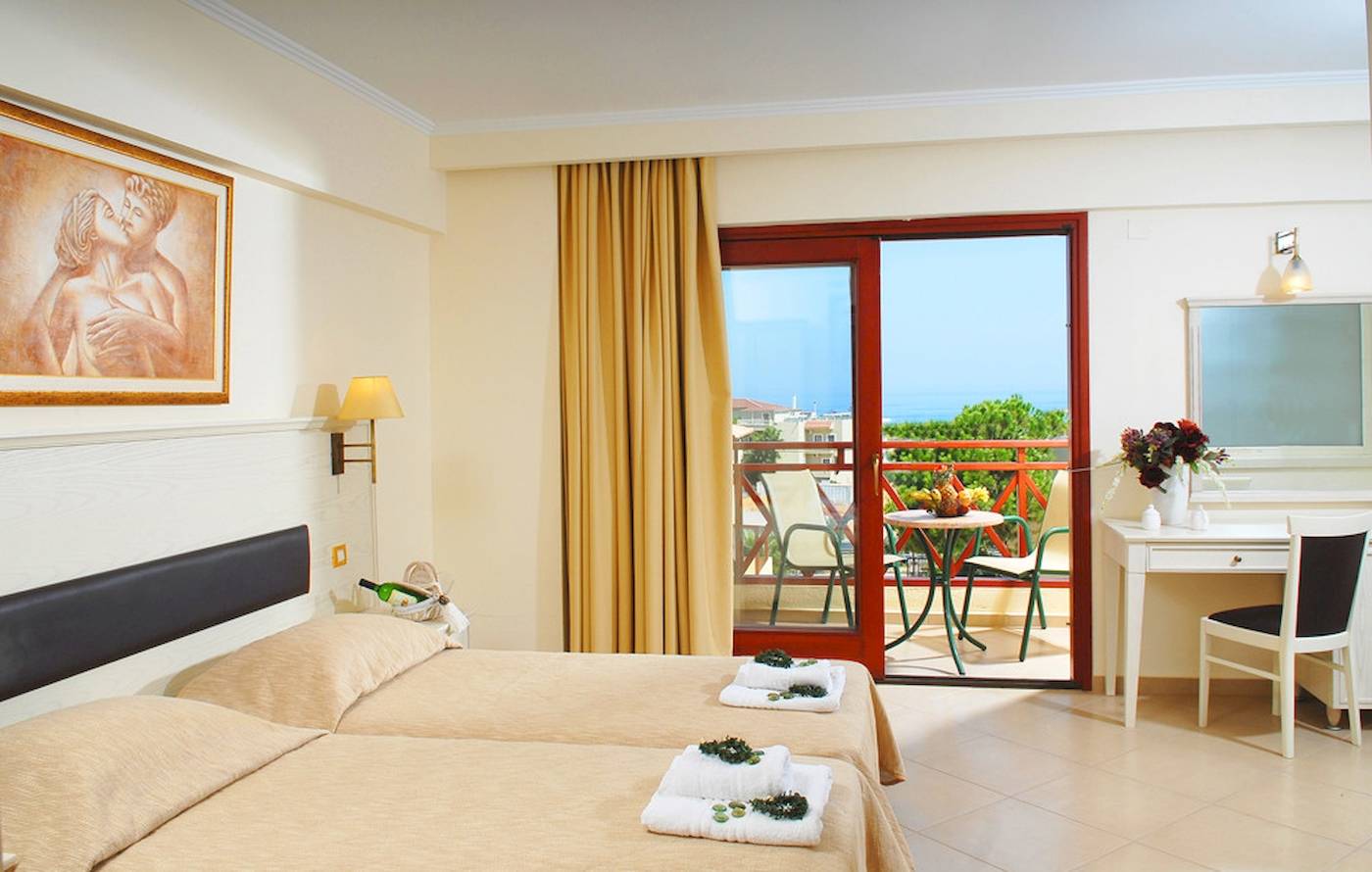 Doppelzimmer mit Balkon im Cactus Village Hotel & Bungalows mit Blick auf den Garten und den Tisch draußen.