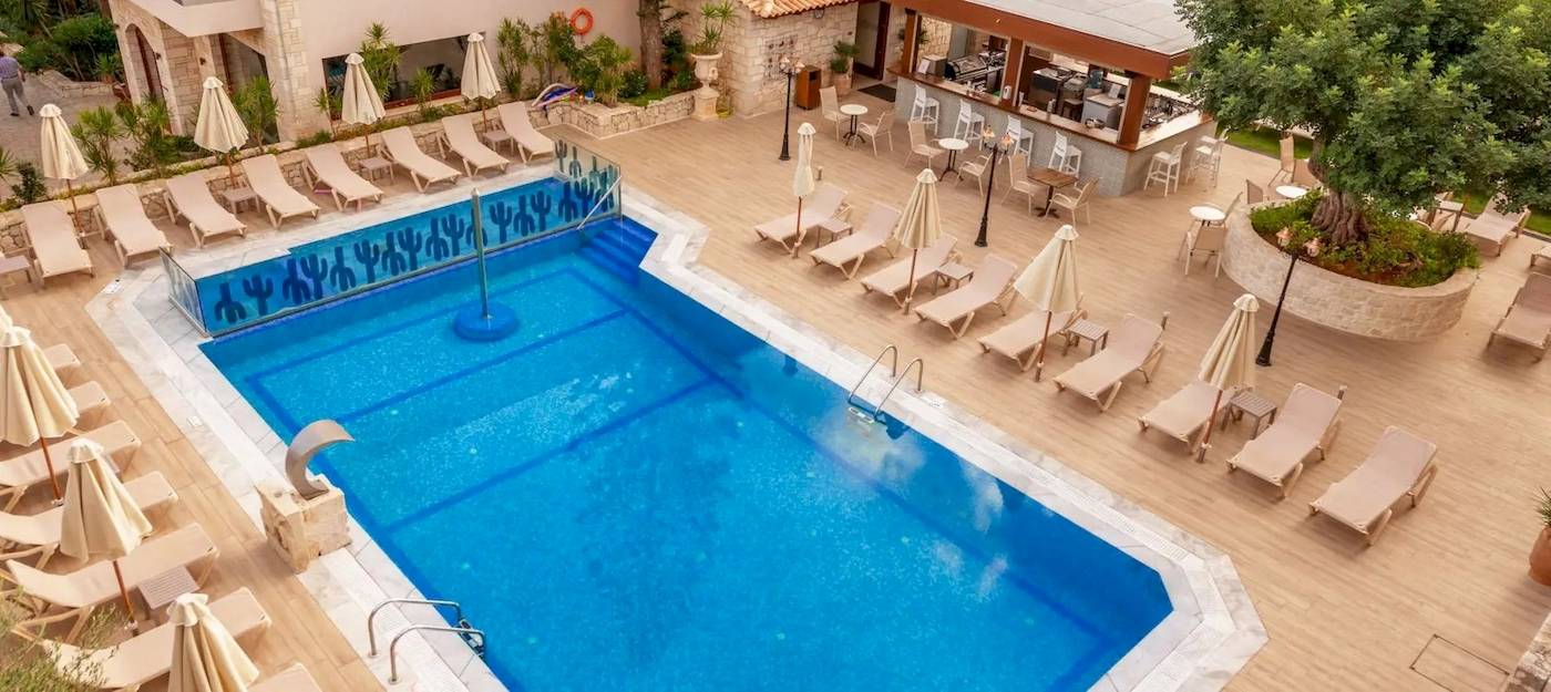 Außenbereich eines Hotels mit Swimmingpool, Liegen und Sonnenschirmen.