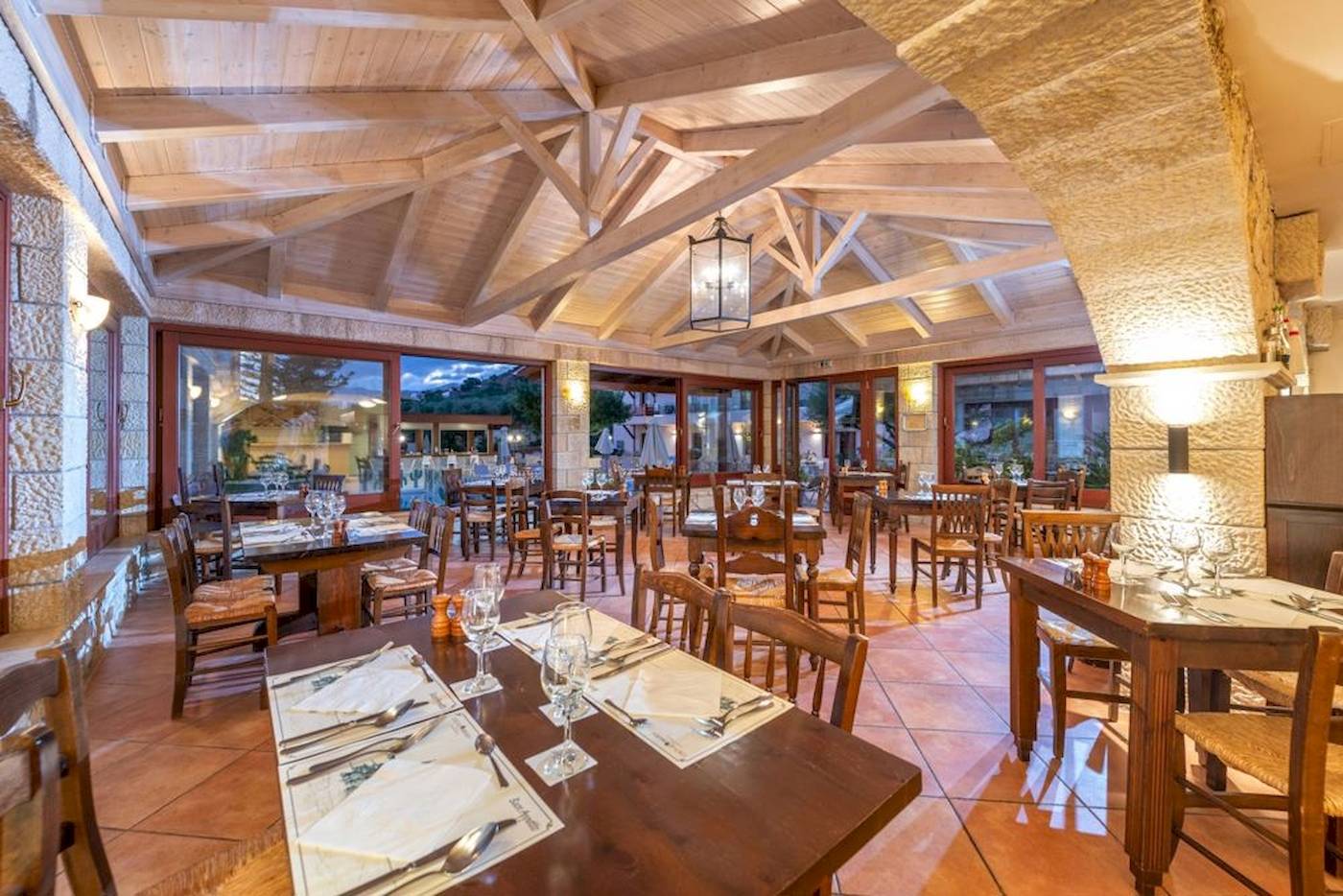 Innenbereich des Restaurants im Cactus Village Hotel & Bungalows mit Holztischen und Stühlen.