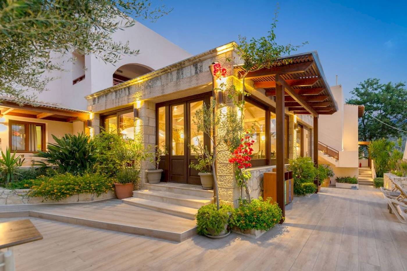 Außenansicht des Cactus Village Hotel & Bungalows mit gepflastertem Eingang und Pflanzen.