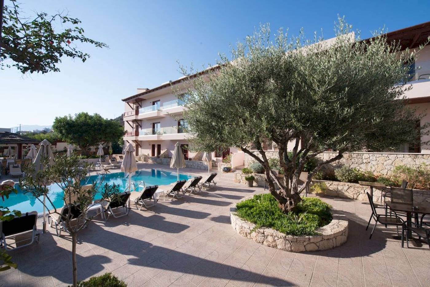 Pool-Lounge-Bereich des Cactus Village Hotel & Bungalows mit Liegen und Sonnenschirmen.