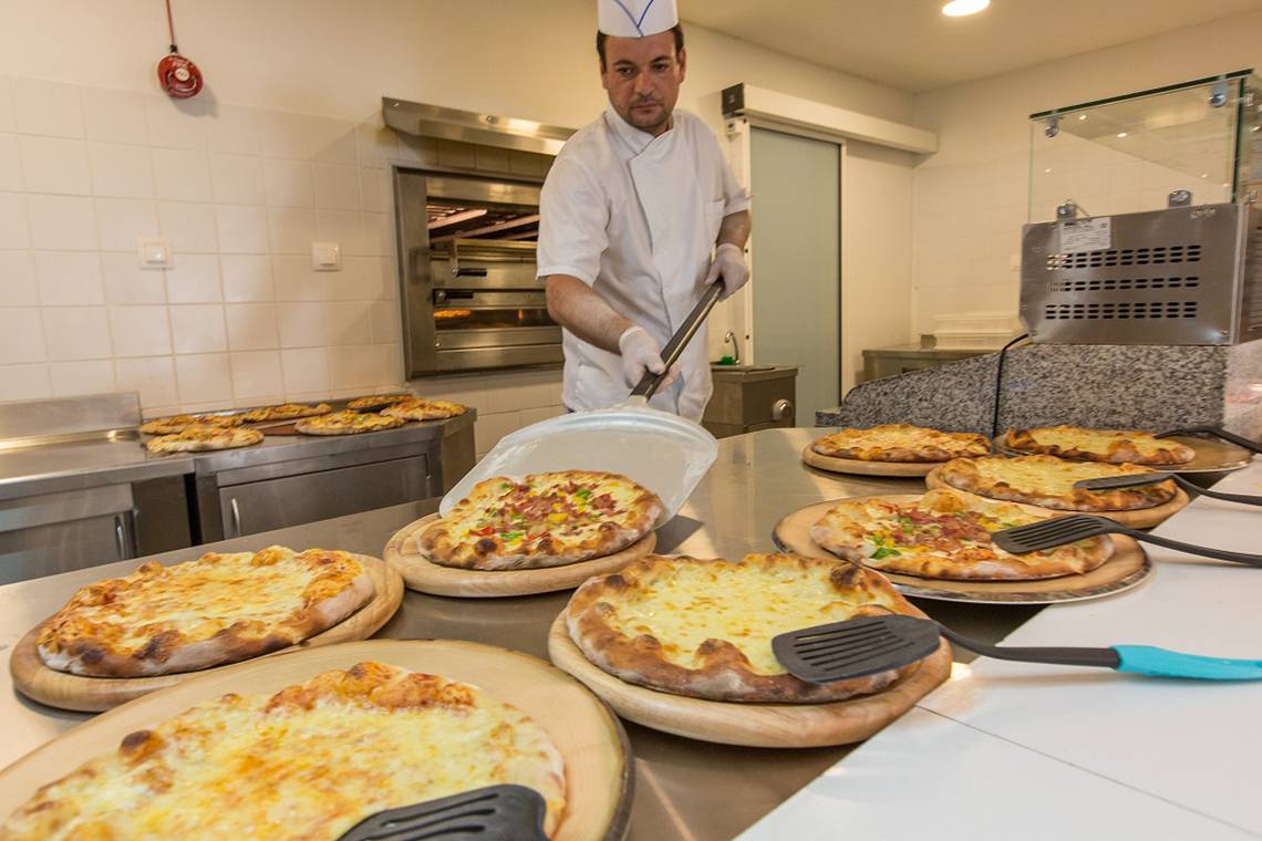 Ein Koch bereitet mehrere Pizzen im Hotel Sun Palace zu.