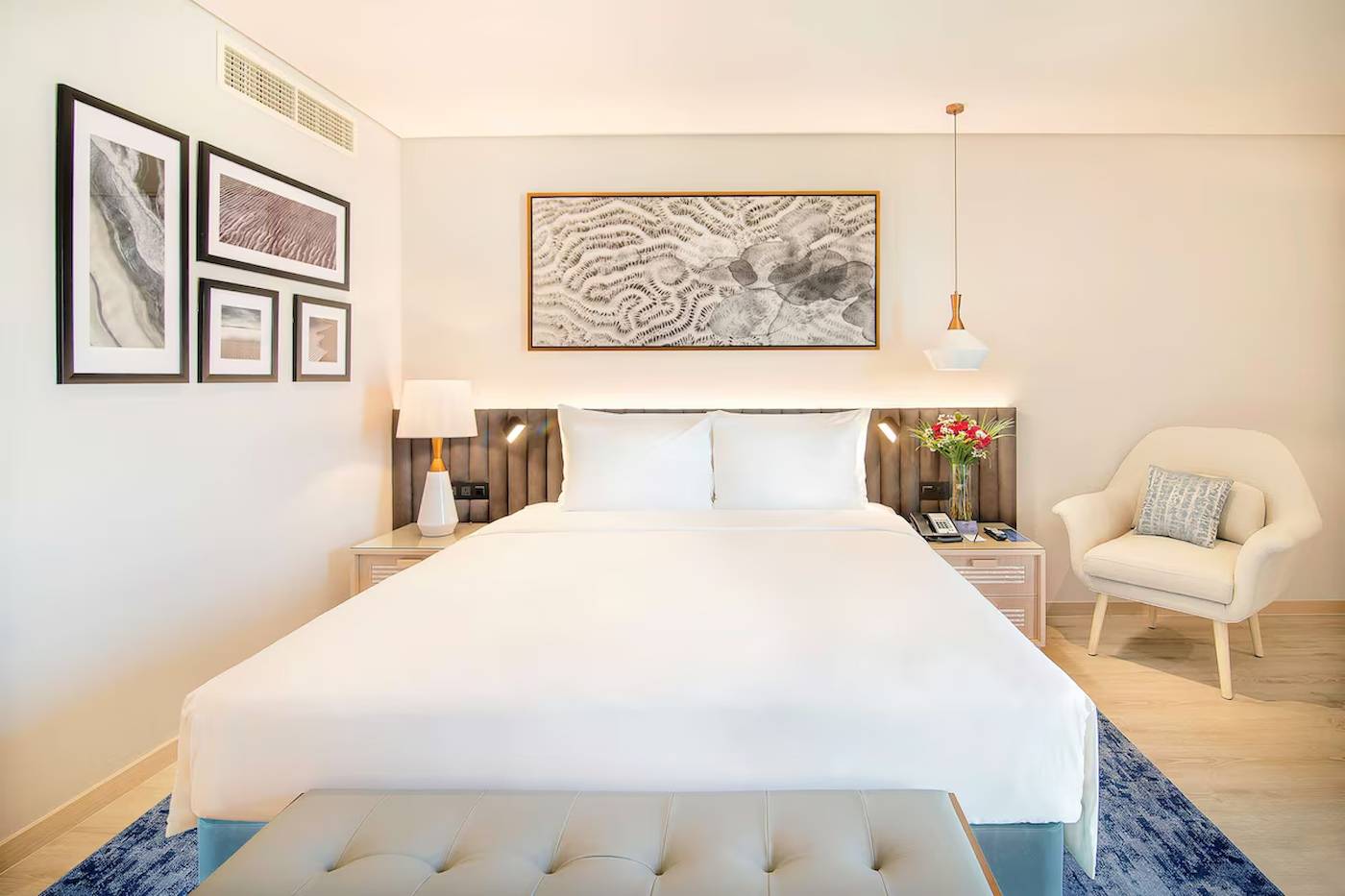 Innenansicht eines Schlafzimmers im Radisson Blu Hotel & Resort, Abu Dhabi Corniche, mit Bett, Nachttischen und Dekor.