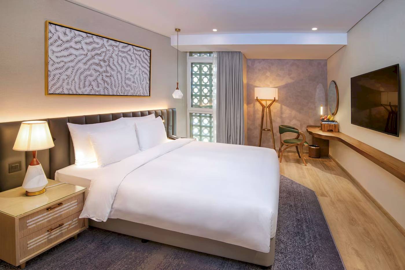 Das moderne Zimmer im Radisson Blu Hotel Abu Dhabi Corniche mit Bett, Lampen und Fernseher.