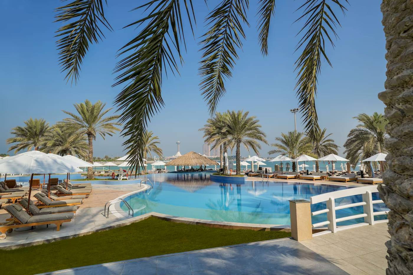 Außenpool des Radisson Blu Hotel & Resort in Abu Dhabi mit Liegestühlen und Sonnenschirmen.