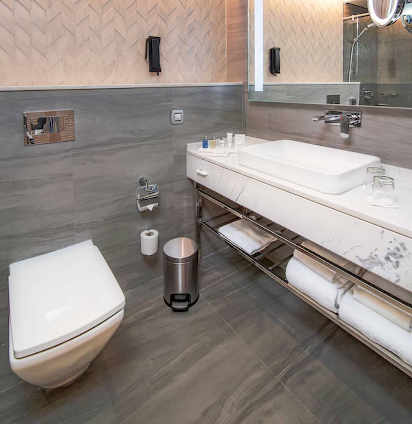 Badezimmer im Radisson Blu Hotel & Resort, Abu Dhabi Corniche mit grauen Wänden, Marmor-Waschtisch und Toilette.